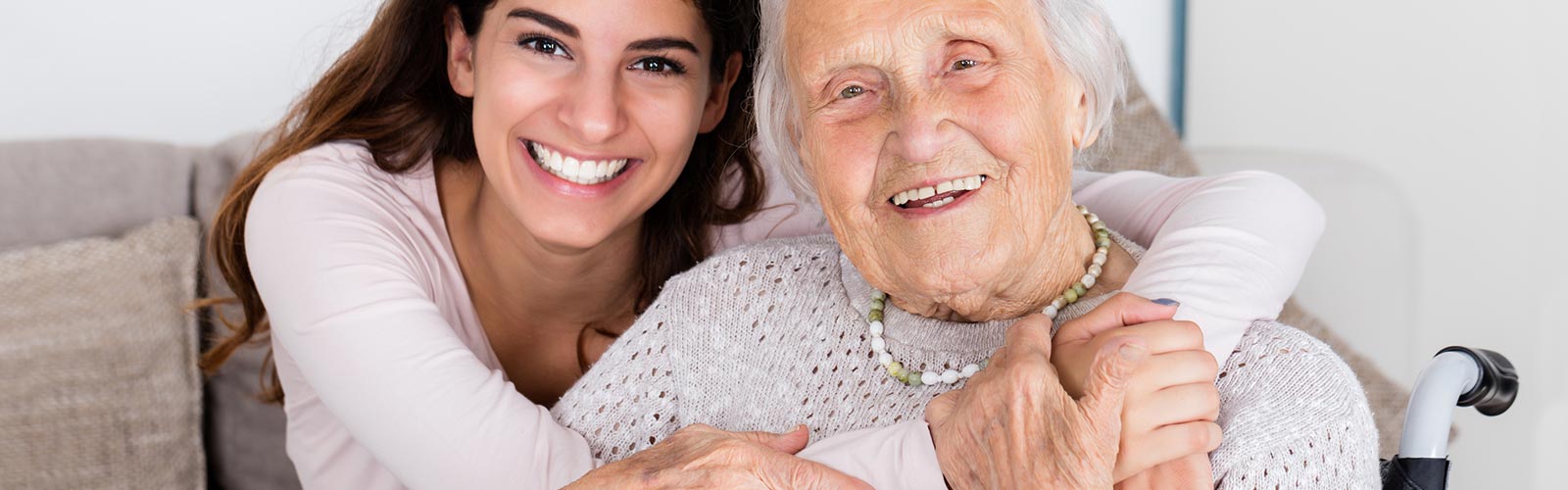 Lächelnde Seniorin und ihre Pflegerin umarmen sich